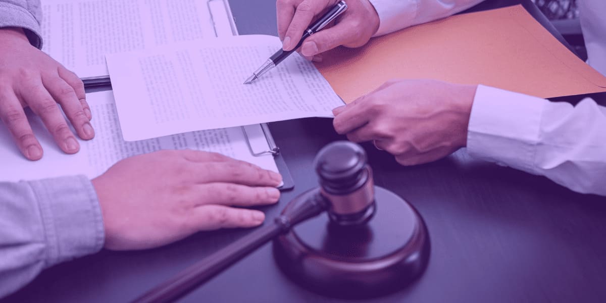 Litigancia-de-ma-fe A imagem retrata uma situação jurídica, onde duas pessoas estão revisando ou assinando documentos sobre uma mesa, sugerindo um ambiente de trabalho legal. No centro, há um documento sendo analisado e uma caneta em ação, simbolizando a formalização de um processo. Um martelo de juiz também está presente, reforçando o contexto jurídico, possivelmente relacionado a julgamentos ou decisões judiciais. O cenário pode remeter a casos de "litigância de má-fé", onde uma das partes age de forma abusiva ou desonesta, utilizando o sistema judiciário com o intuito de enganar ou prejudicar a outra parte.