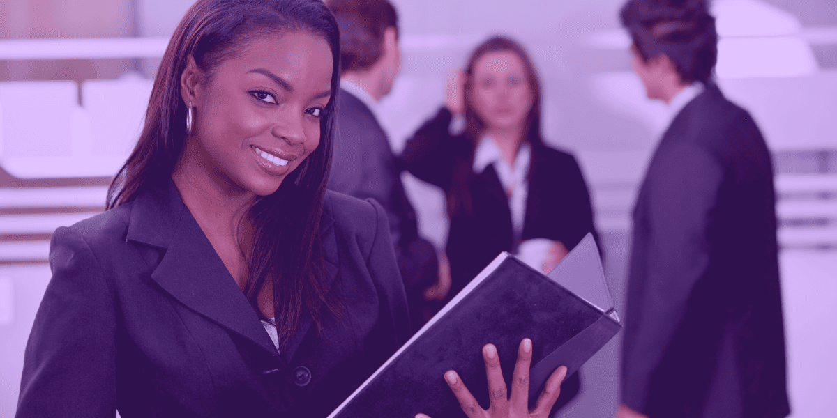 desconsideração da personalidade jurídica Uma advogada sorridente segura uma pasta em um ambiente corporativo, com colegas conversando ao fundo.