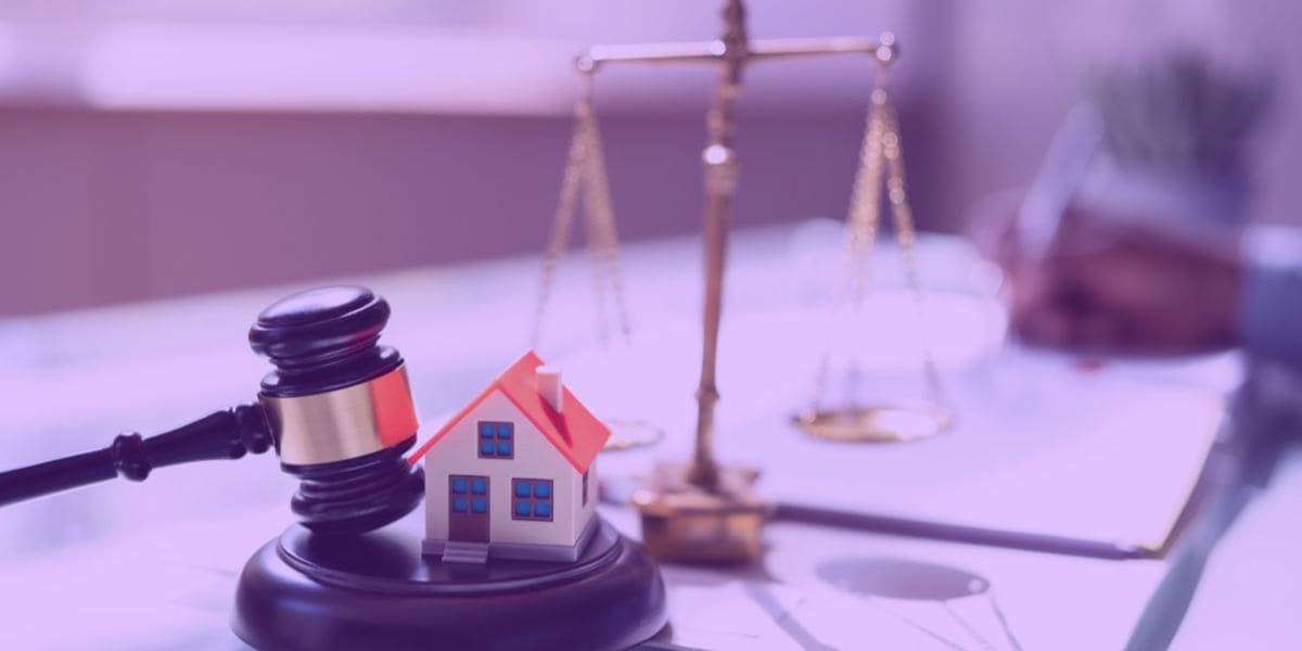 usucapião Um advogado escrevendo uma ação de usucapião, ao lado, um martelo da justiça, uma miniatura de uma casa e a balança representando a justiça.