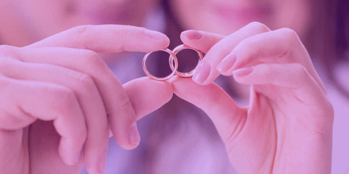comunhão parcial de bens Um casal segurando as alianças de casamento, simbolizando a comunhão parcial de bens.
