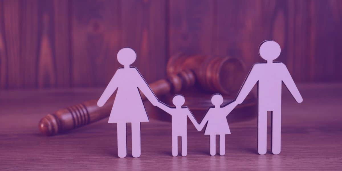 A imagem retrata figuras de uma família (pai, mãe e dois filhos) segurando as mãos, posicionadas em frente a um martelo de juiz, sugerindo uma temática relacionada ao Direito de Família, como guarda compartilhada.