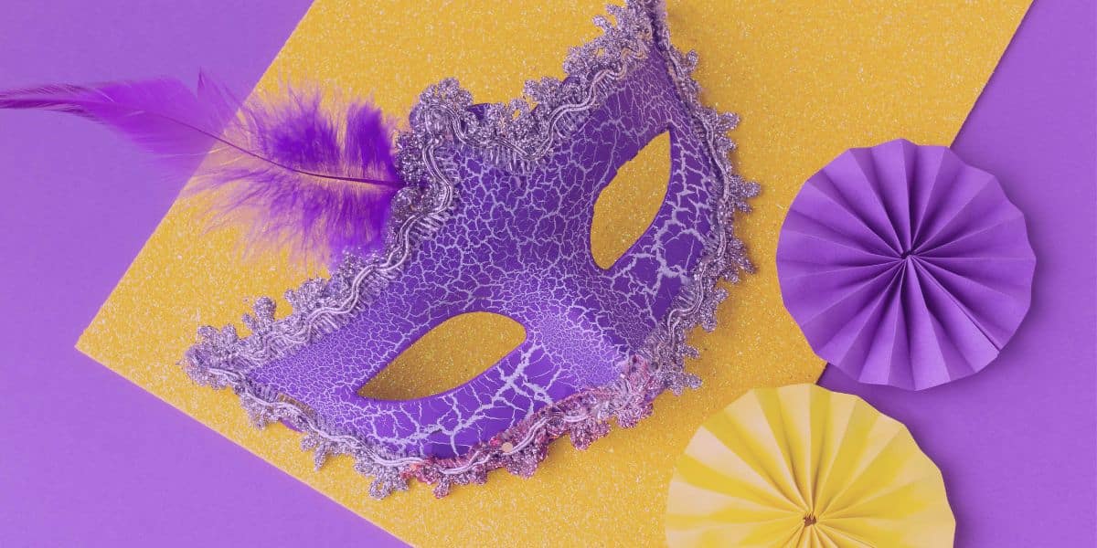 Carnaval TJSP 2025 Carnaval TJSP 2025: Uma máscara roxa e, ao lado, uns enfeites nas cores roxa e amarela.