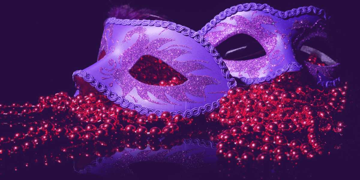 carnaval-tjba-2025 Carnaval TJBA 2025: duas máscaras roxas e enfeites de bolinha vermelha em volta.
