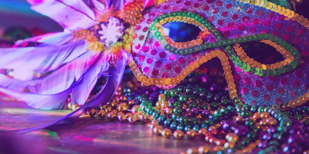 carnaval-tjrs-2025 Carnaval TJRS 2025: uma máscara de carnaval colorida e enfeites coloridos ao redor.